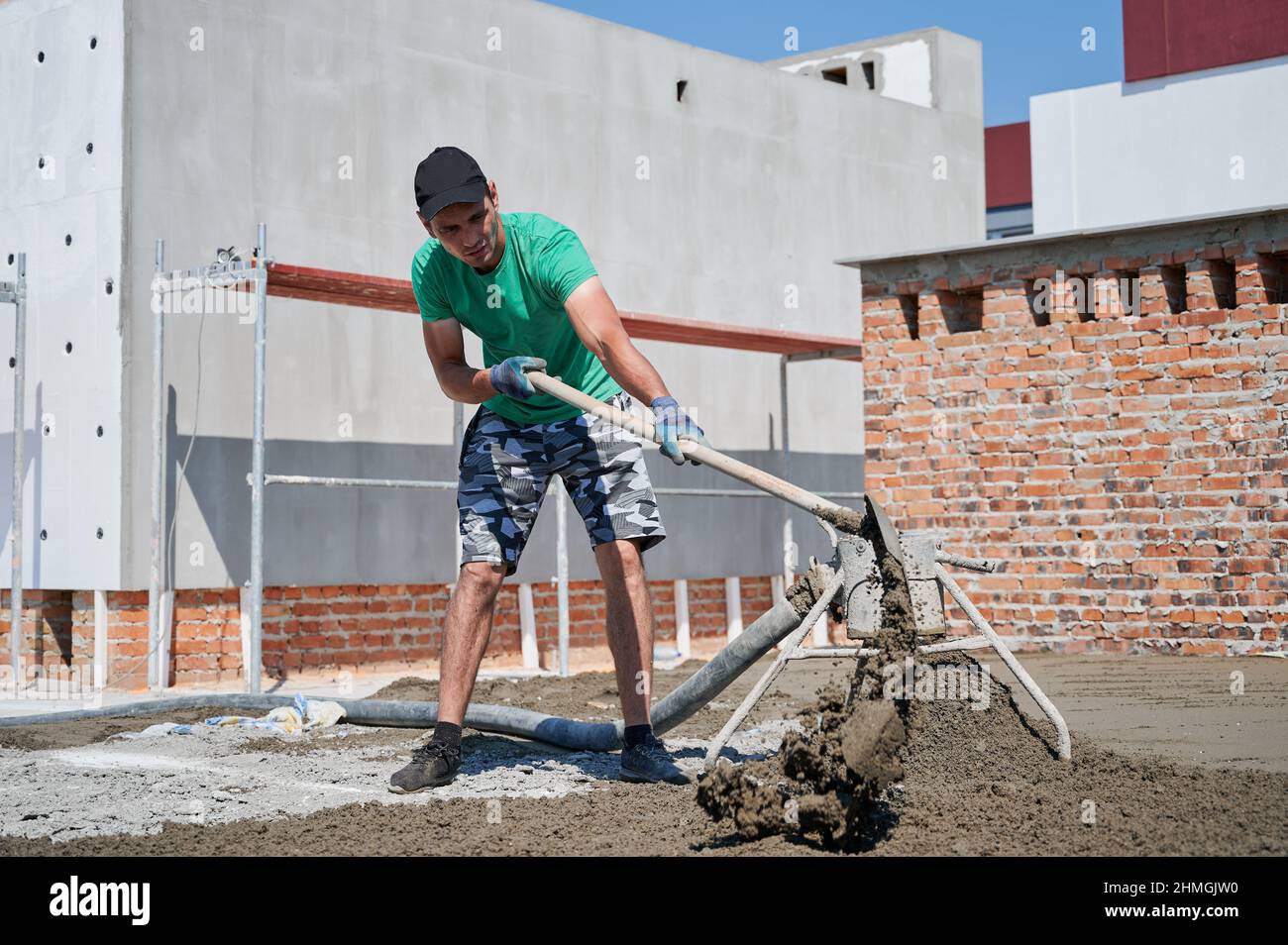 Male worker shoveling sand-cement mix while working at 
