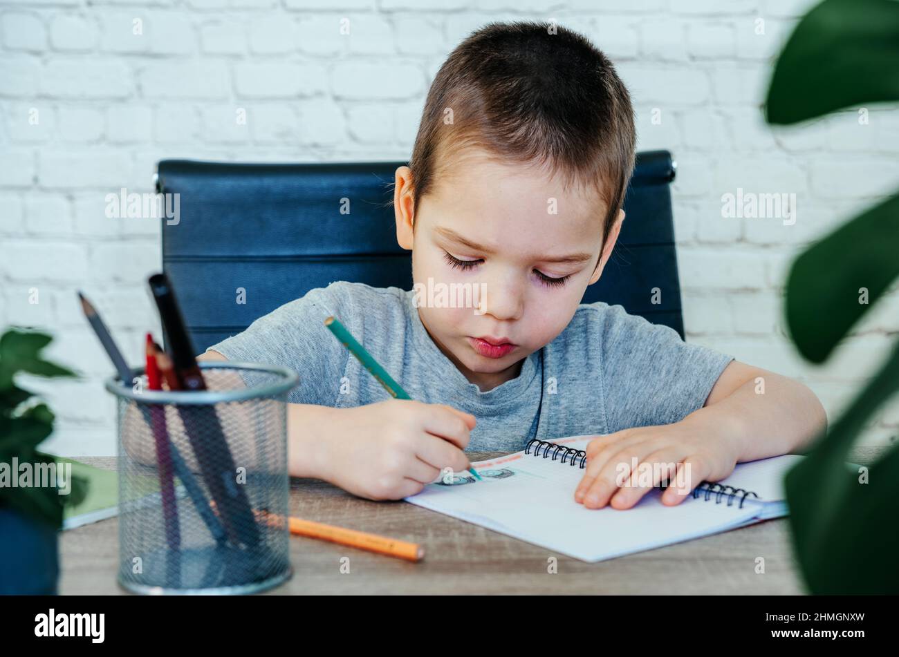 Cute little boy drawing in his notebook at the table Stock Photo - Alamy