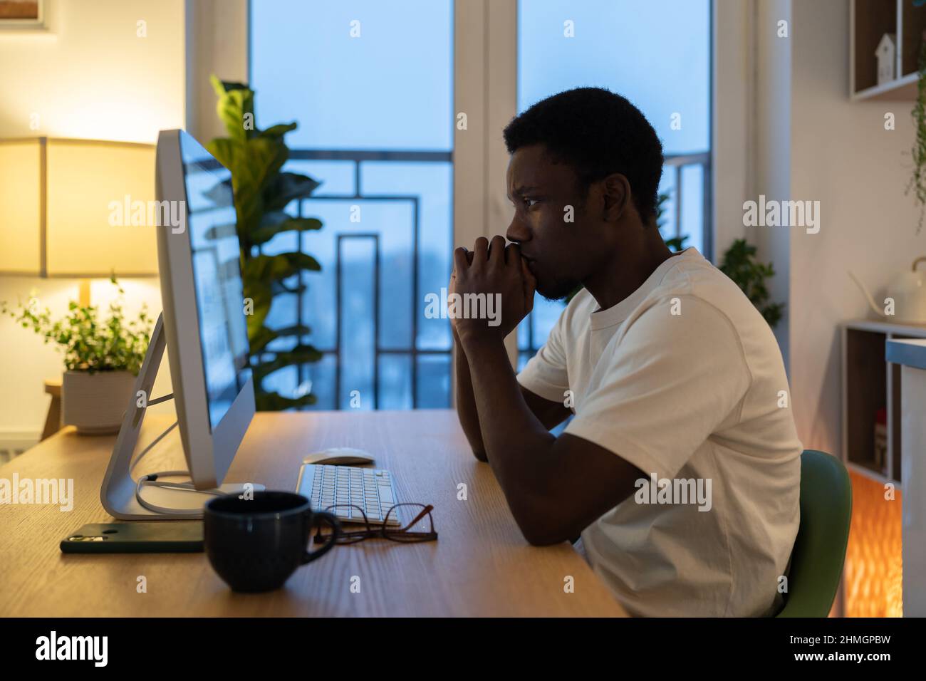 Pensive freelance programmer thoughtful work on application software or website serious look at pc Stock Photo