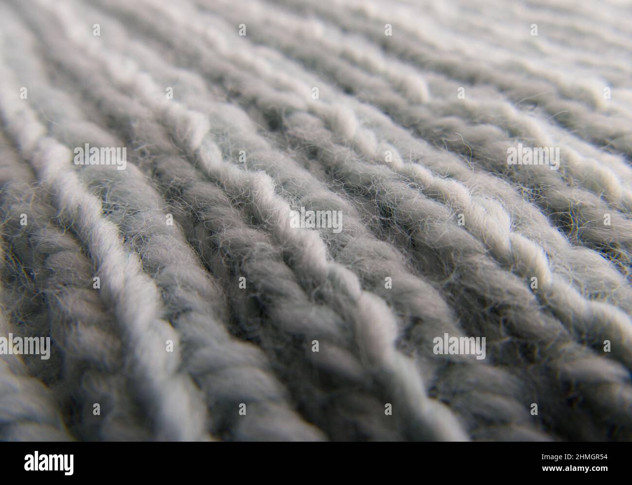 Macro close-up of hand-knitted garment (2x2 rib stitch) in pale blue. Diagonal view. Stock Photo
