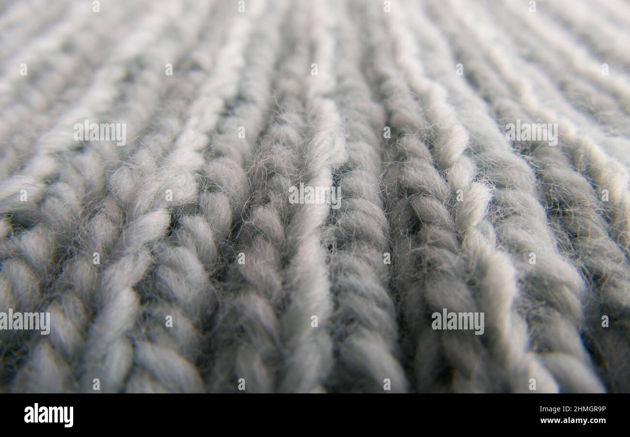 Macro close-up of hand-knitted garment (2x2 rib stitch) in pale blue. Vertical view. Stock Photo