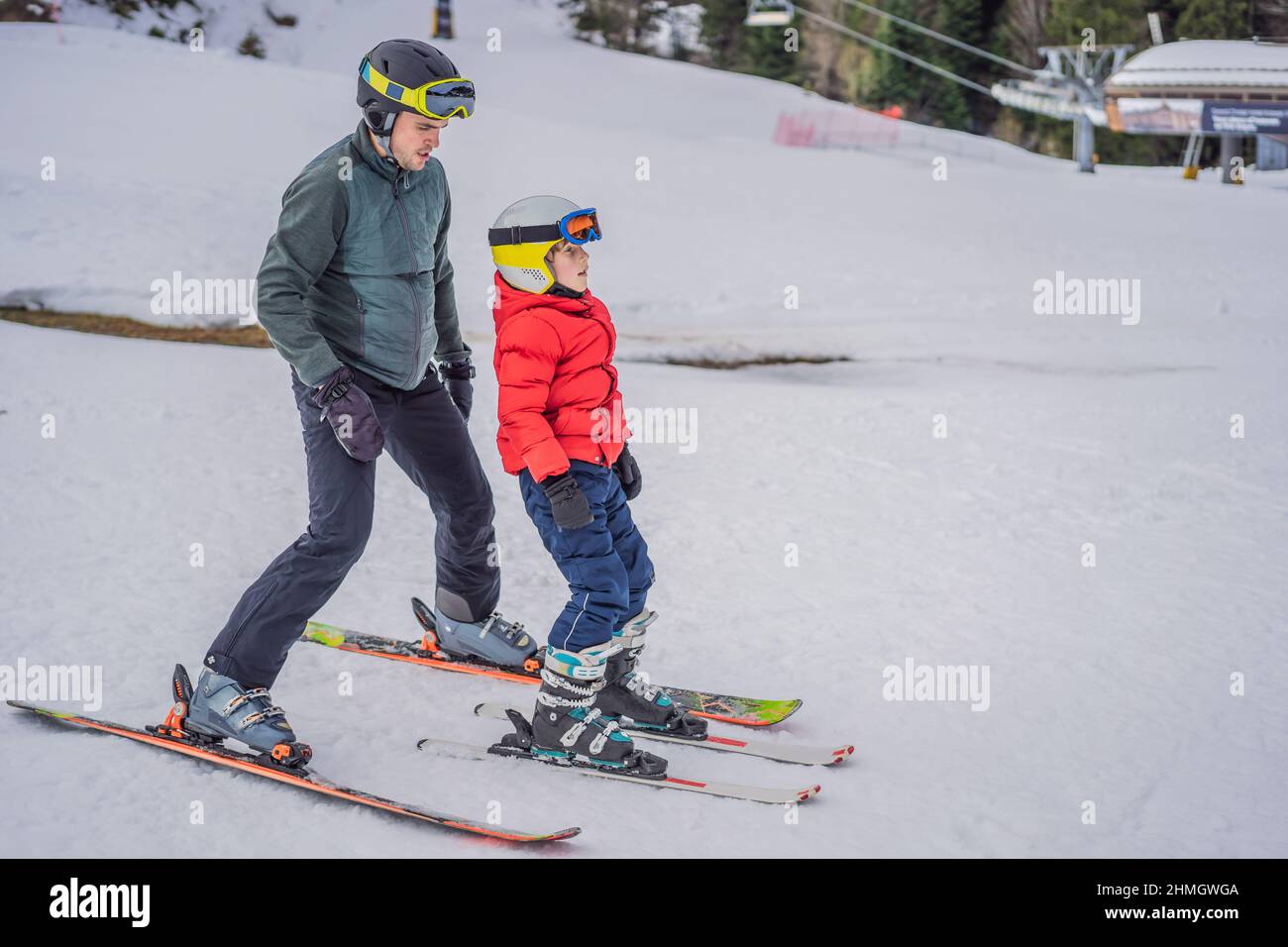 Boy learning to ski, training and listening to his ski instructor on the slope in winter Stock Photo