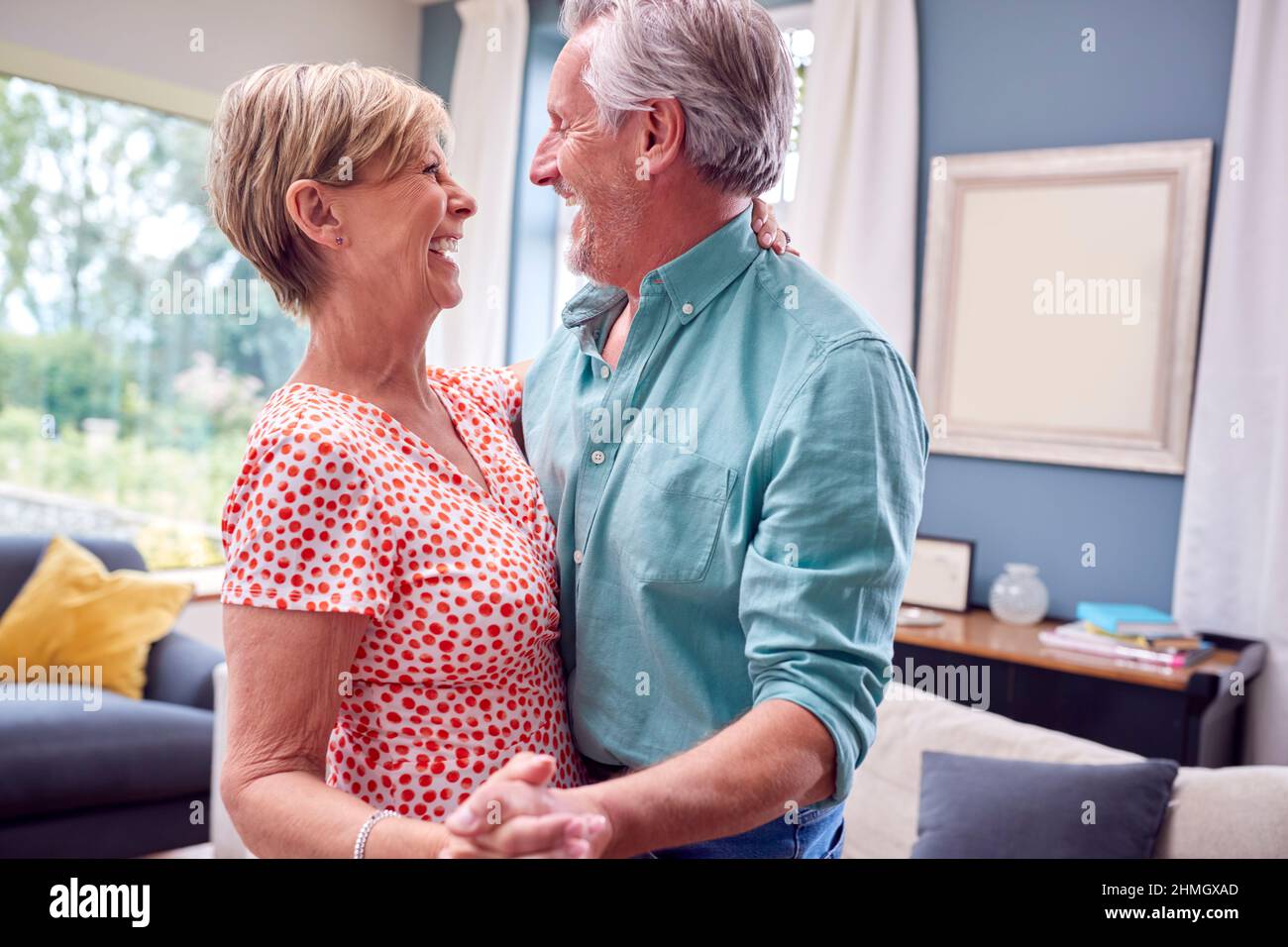 Romantic Senior Retired Couple Dancing In Lounge At Home Together Stock
