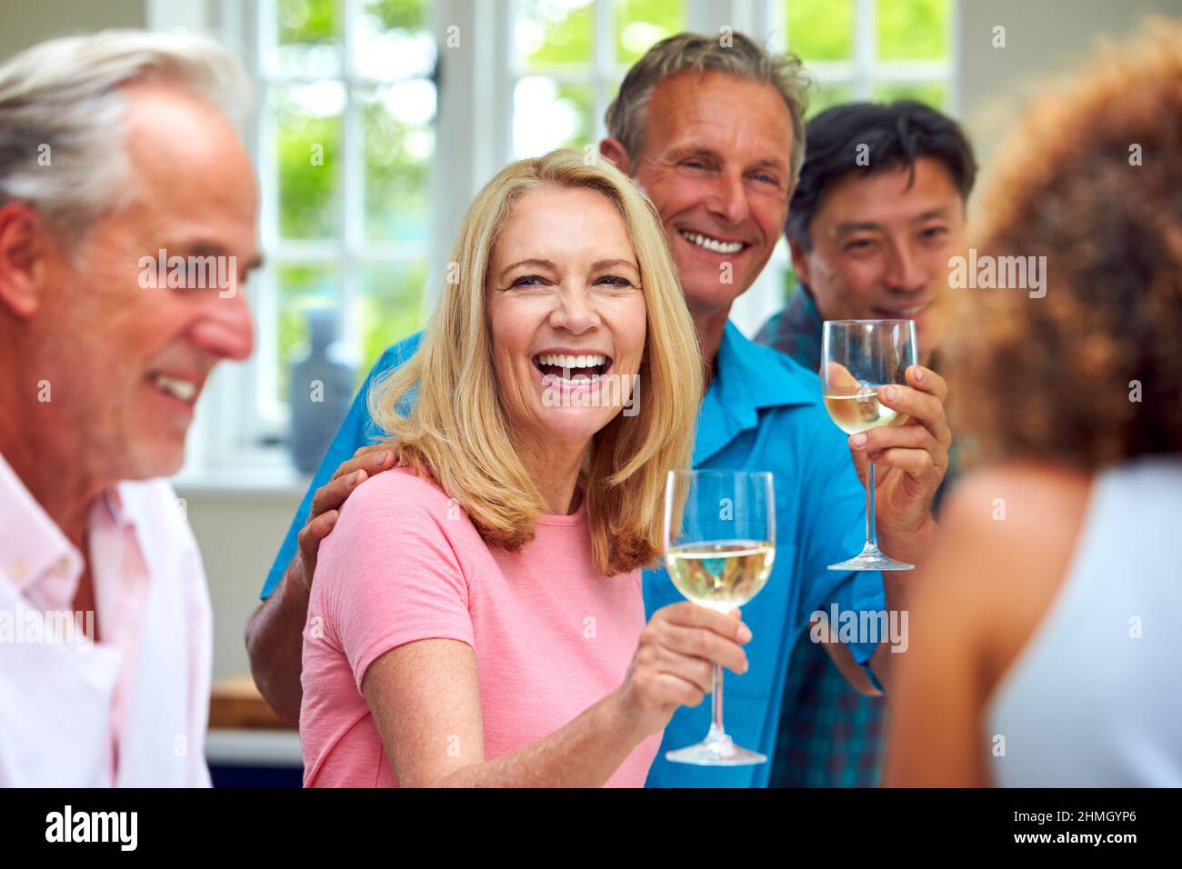 Group Of Multi-Cultural Senior Friends On Summer Vacation Meeting For Drinks In Holiday Apartment Stock Photo