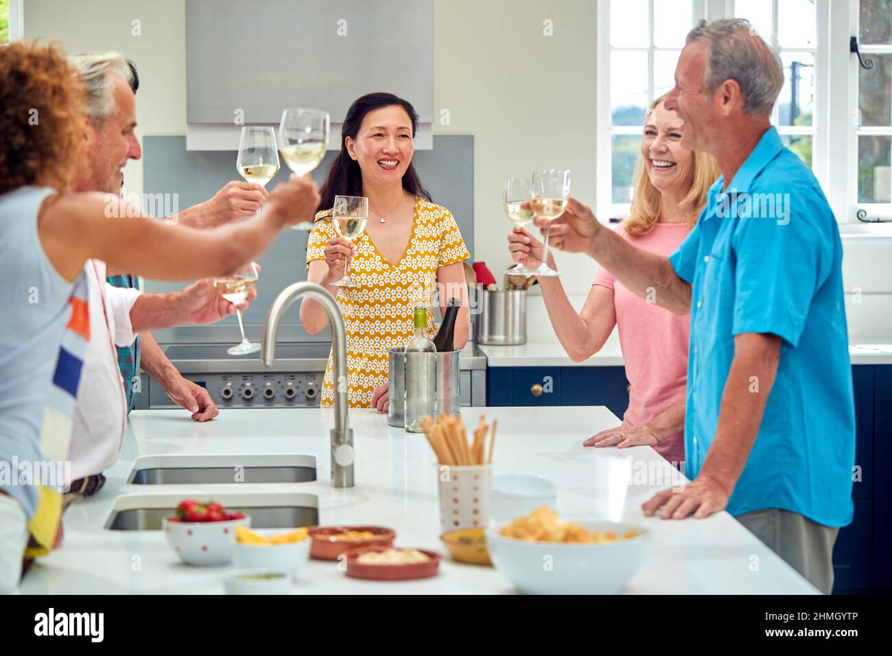 Group Of Multi-Cultural Senior Friends On Summer Vacation Meeting For Drinks In Holiday Apartment Stock Photo