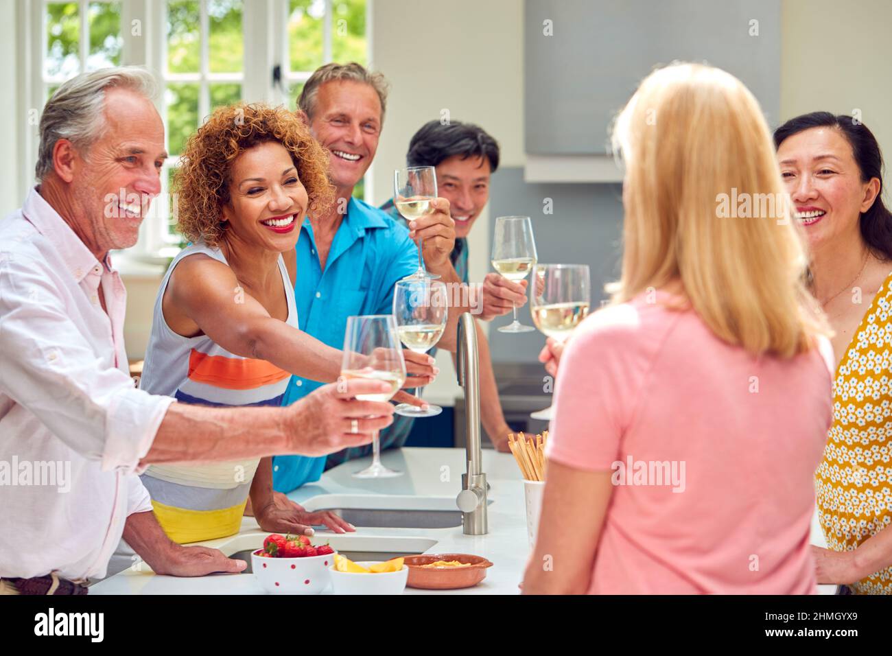 Group Of Multi-Cultural Senior Friends On Summer Vacation Meeting For Drinks In Holiday Apartment Stock Photo