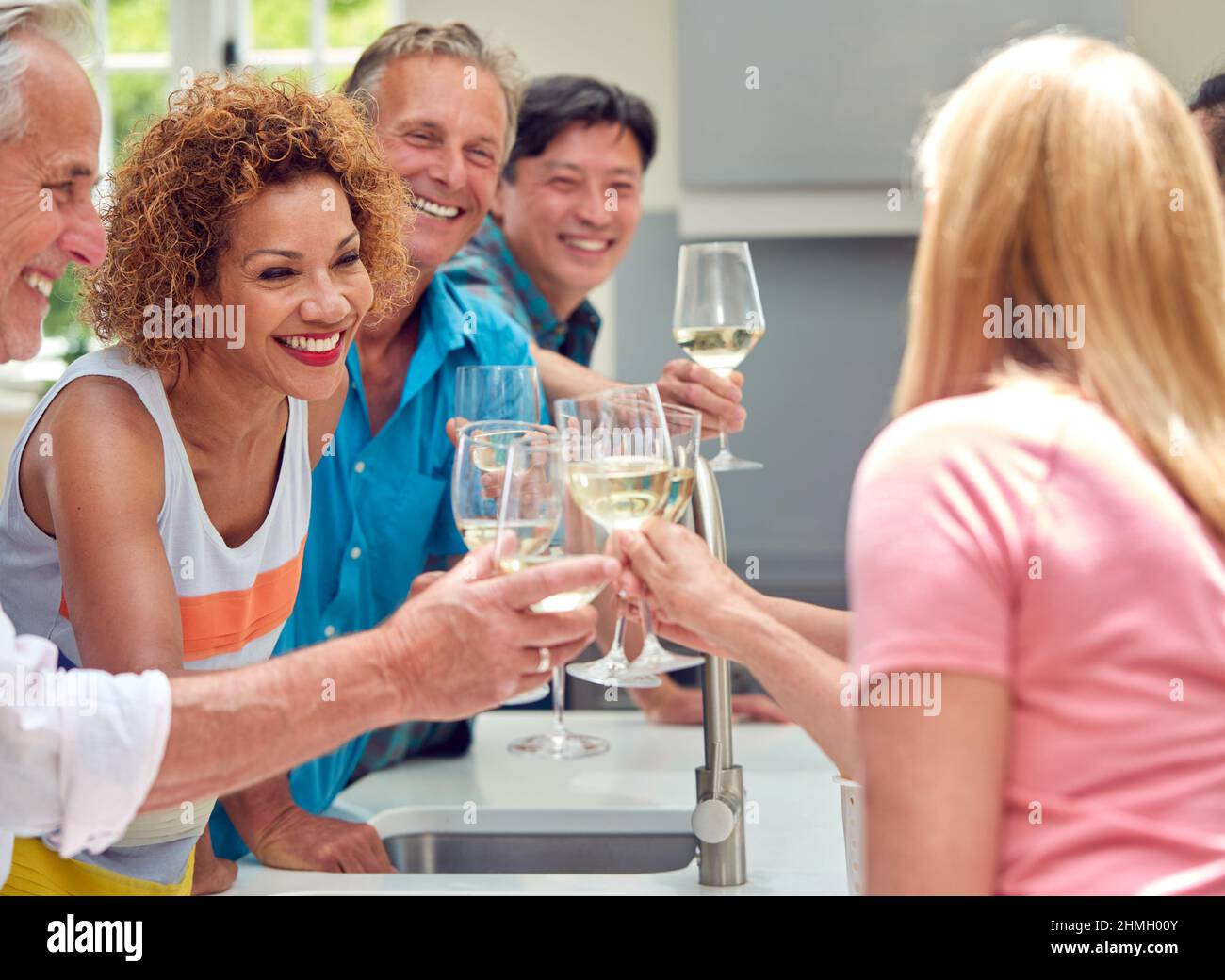 Group Of Multi-Cultural Senior Friends On Summer Vacation Meeting For Drinks In Holiday Apartment Stock Photo