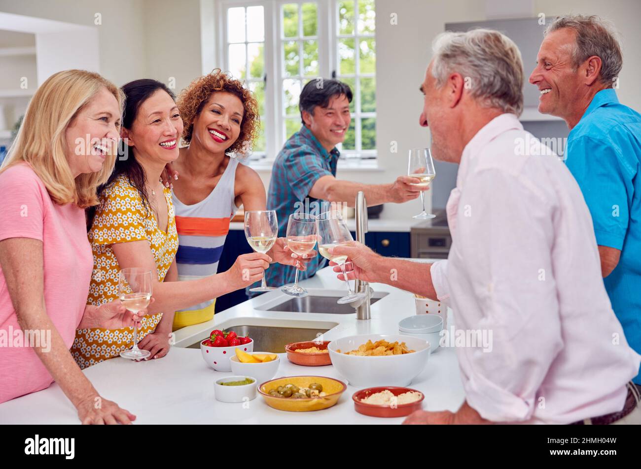 Group Of Multi-Cultural Senior Friends On Summer Vacation Meeting For Drinks In Holiday Apartment Stock Photo