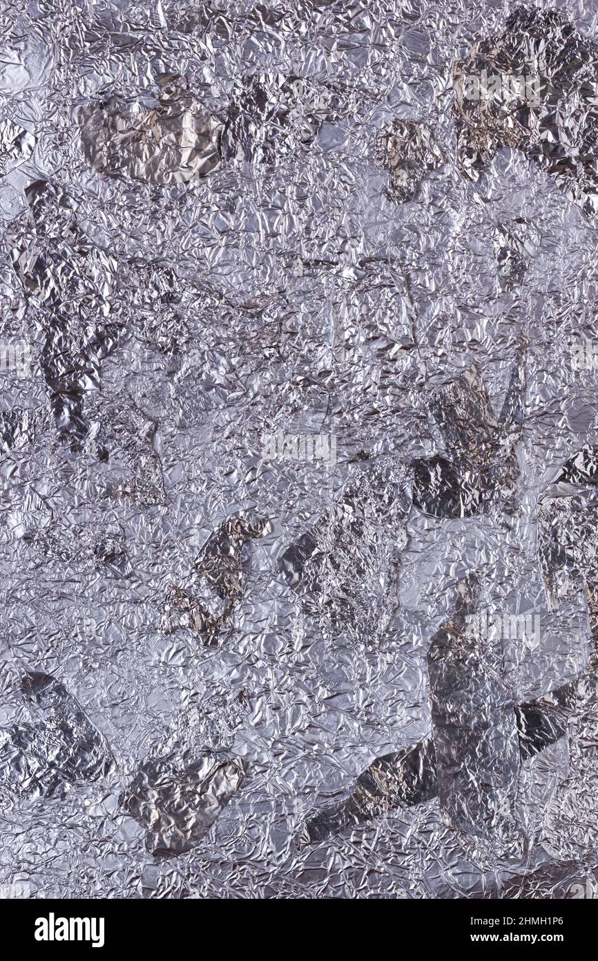 Shiny heavily wrinkled metal silver gray foil vertical texture background for design Stock Photo