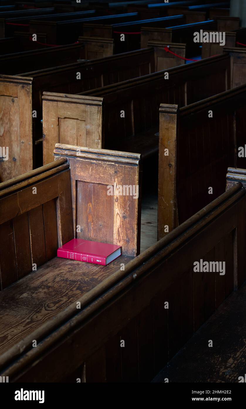 Red Bible On Pine Pews Illuminated By A Window In The Church Of St Peter and St Paul, Ringwood UK Stock Photo
