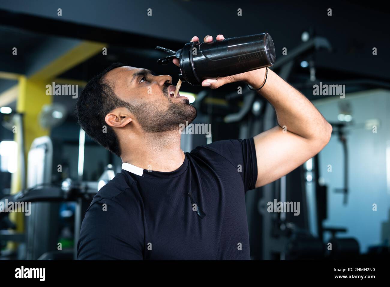 bodybuilder drinking or taking protein powder and mixing with water on bottle by shaking at gym - concpet of muscular gain, fitness training and Stock Photo