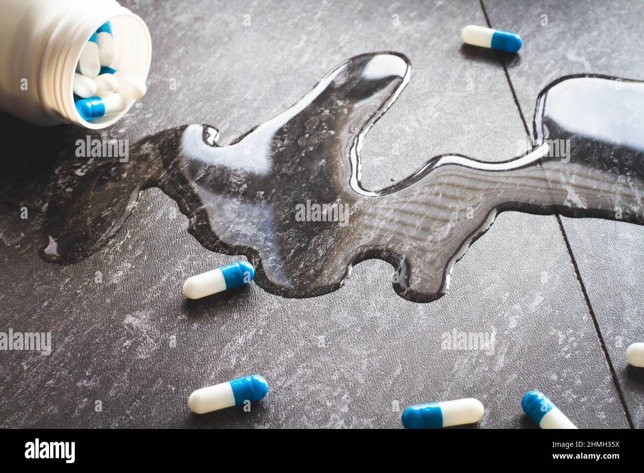 Tablets. Dropping pills and a glass of water from the hands. Stock Photo