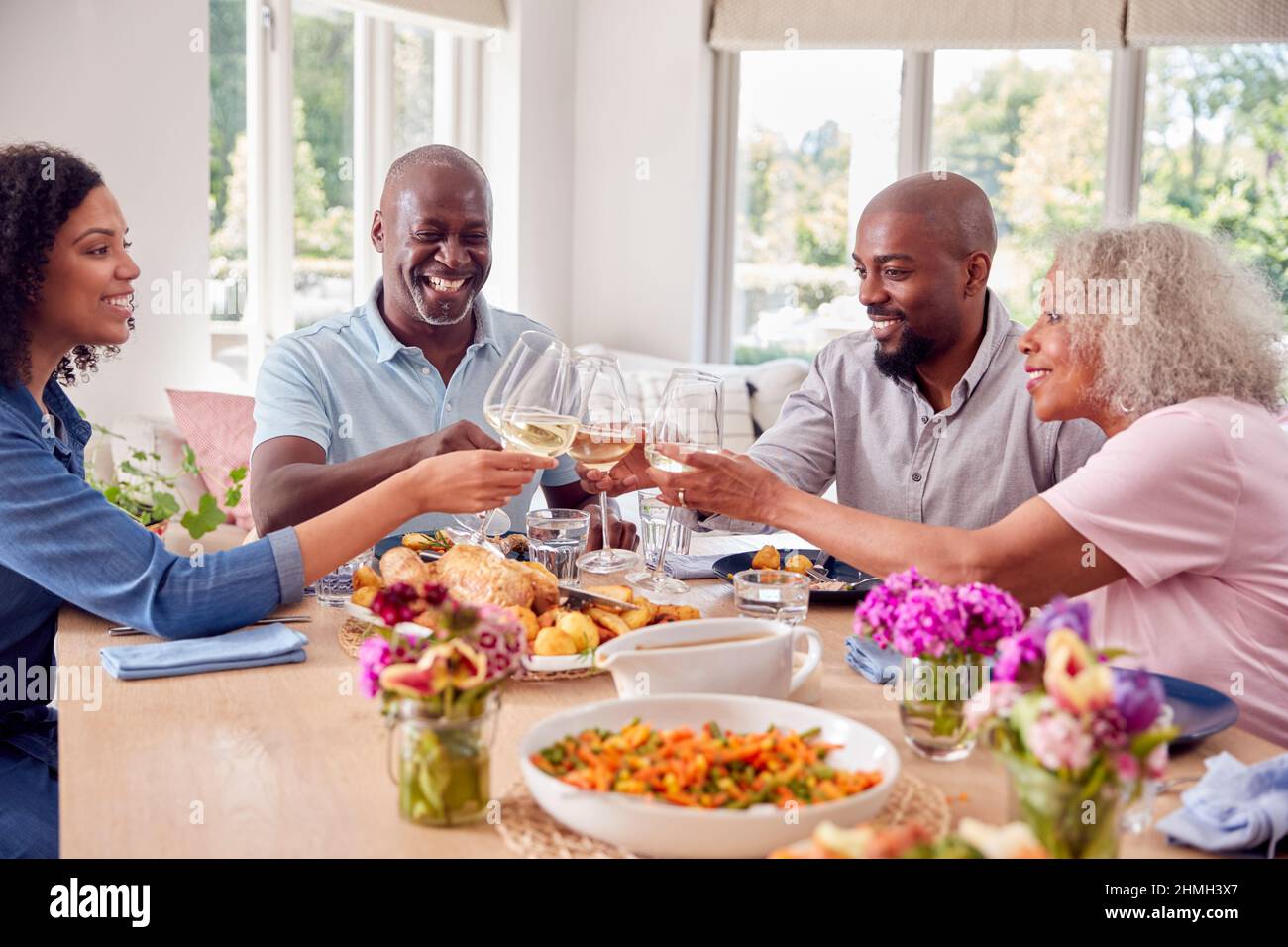 Senior Parents With Adult Offspring Making Toast Sitting Around Table