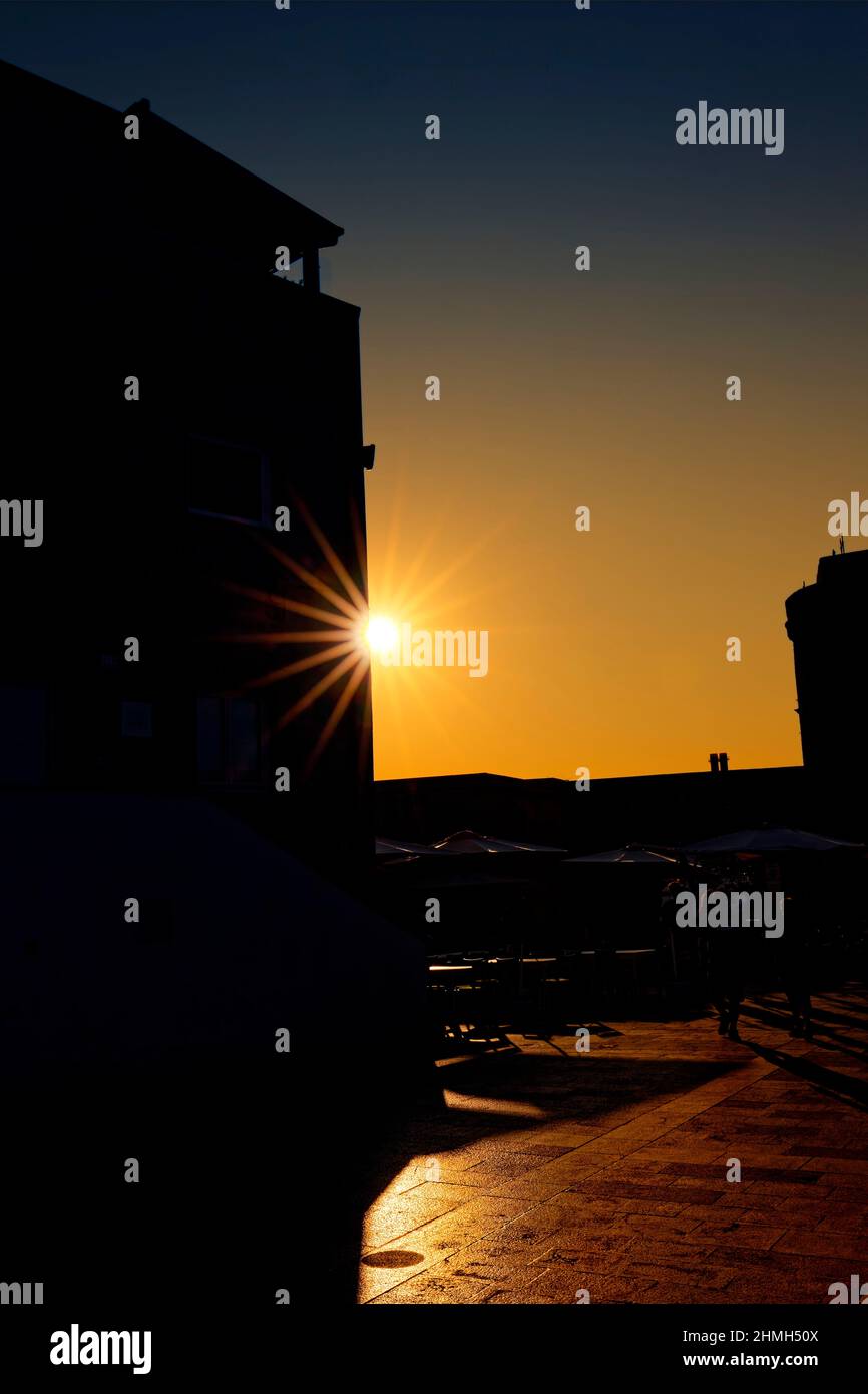 The sun peers past a house wall as a sun star Stock Photo