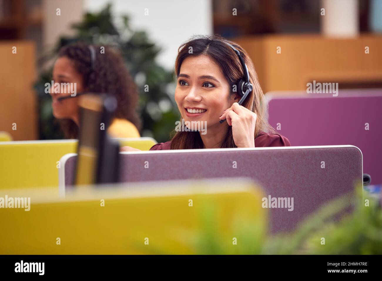 Mature Businesswoman Wearing Phone Headset Talking To Caller In Busy