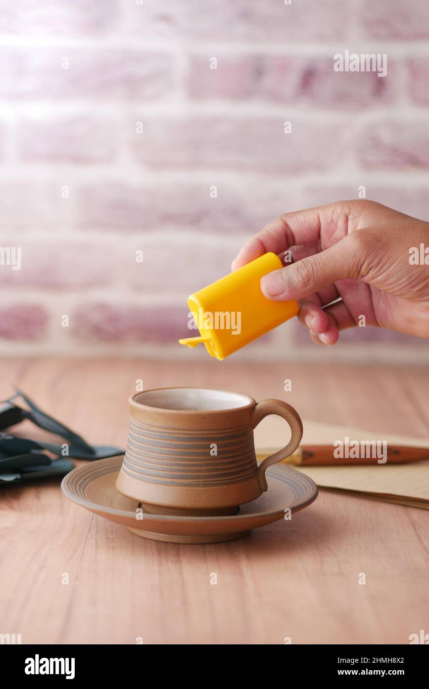 young man putting artificial sweetener in tea, Stock Photo