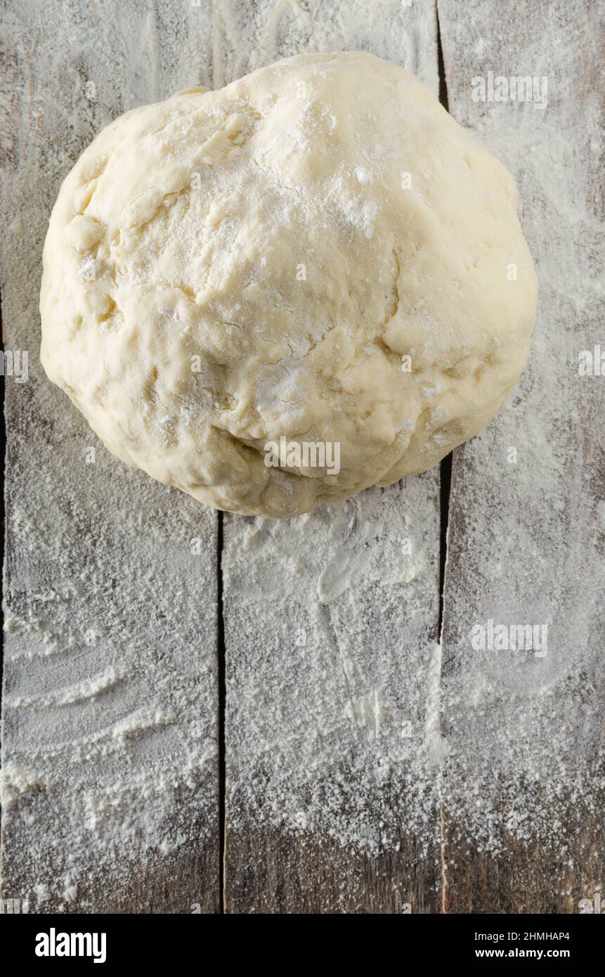 Kneaded dough on the old wooden table sprinkled with flour Stock Photo ...