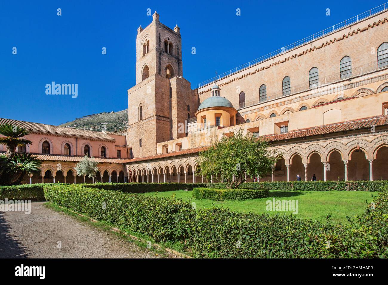 Cloister with garden of the Benedettino monastery at the cathedral with clock tower, Monreale, Sicily, Italy Stock Photo