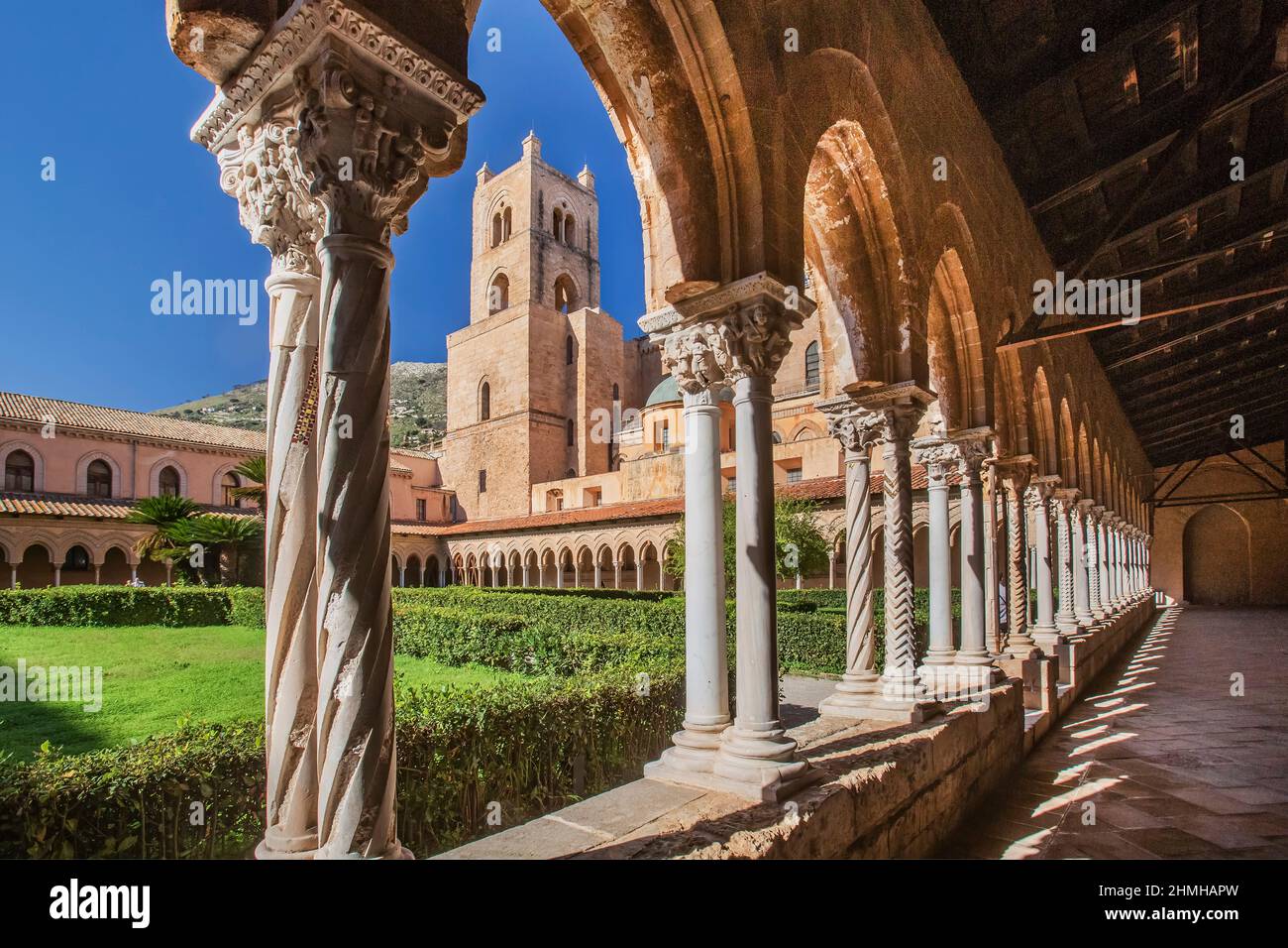 Cloister with garden of the Benedettino monastery at the cathedral with clock tower, Monreale, Sicily, Italy Stock Photo