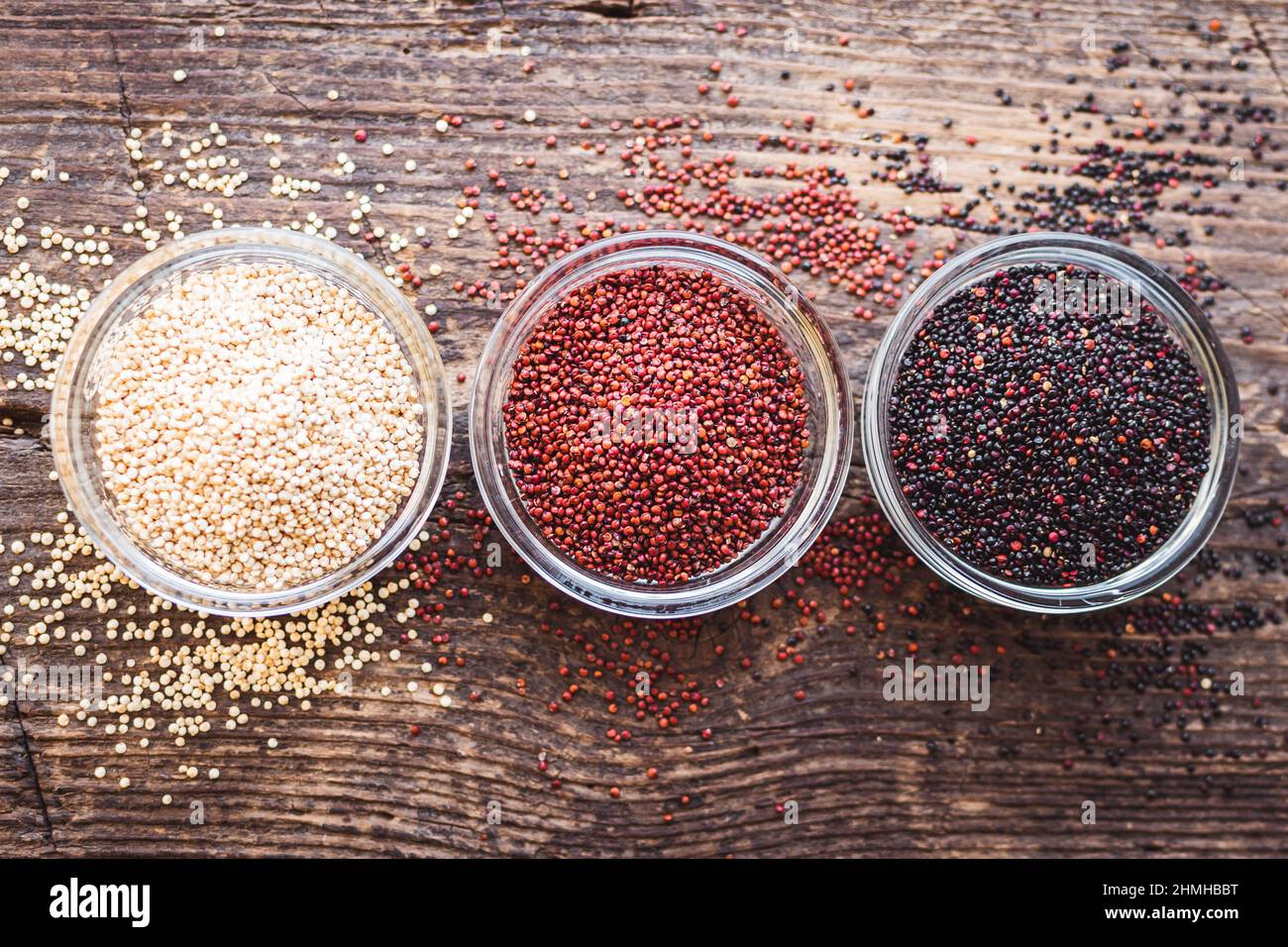 Black, red and white quinoa grains on wooden background. Healthy food. Top view. Stock Photo