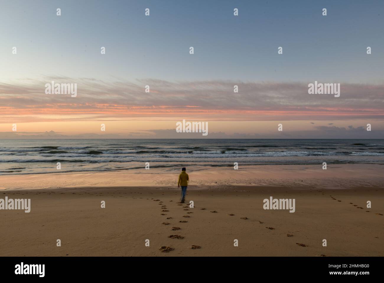 Woman runs towards the ocean surf at sunrise on the Atlantic coast Stock Photo