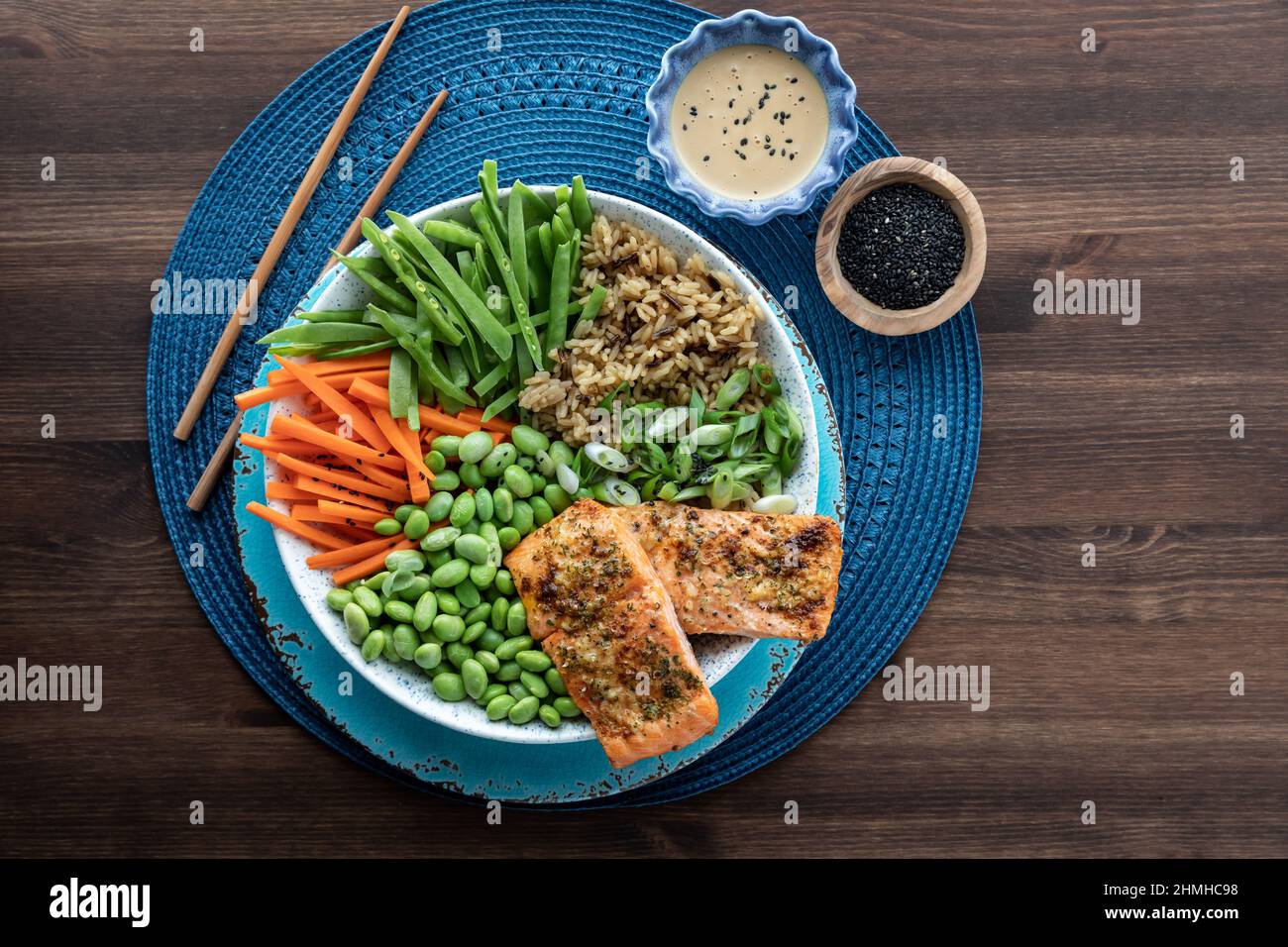 Top down view of an Asian salmon salad bowl with toppings on a wooden table. Stock Photo