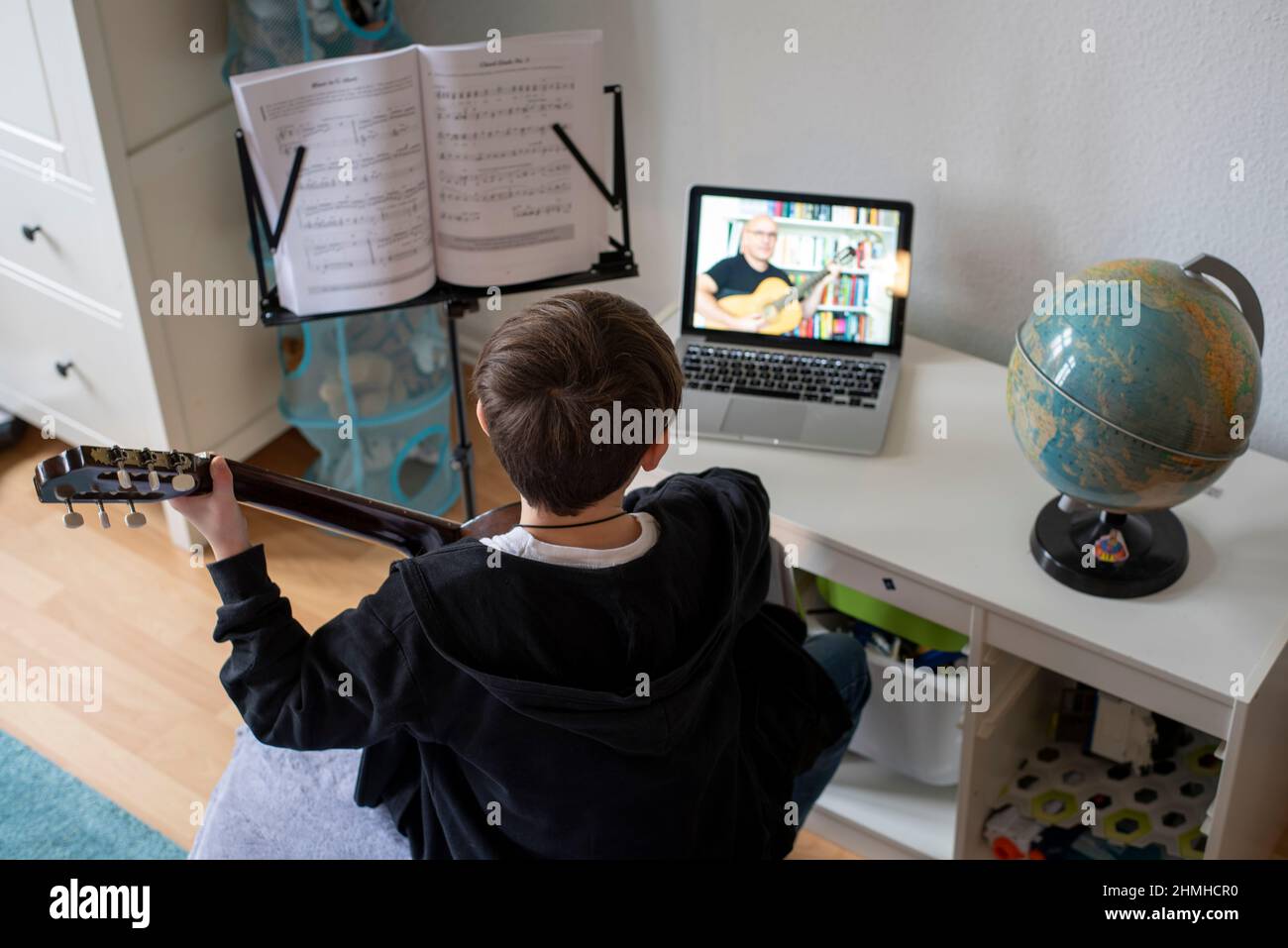 Boy learns guitar in online class. Stock Photo