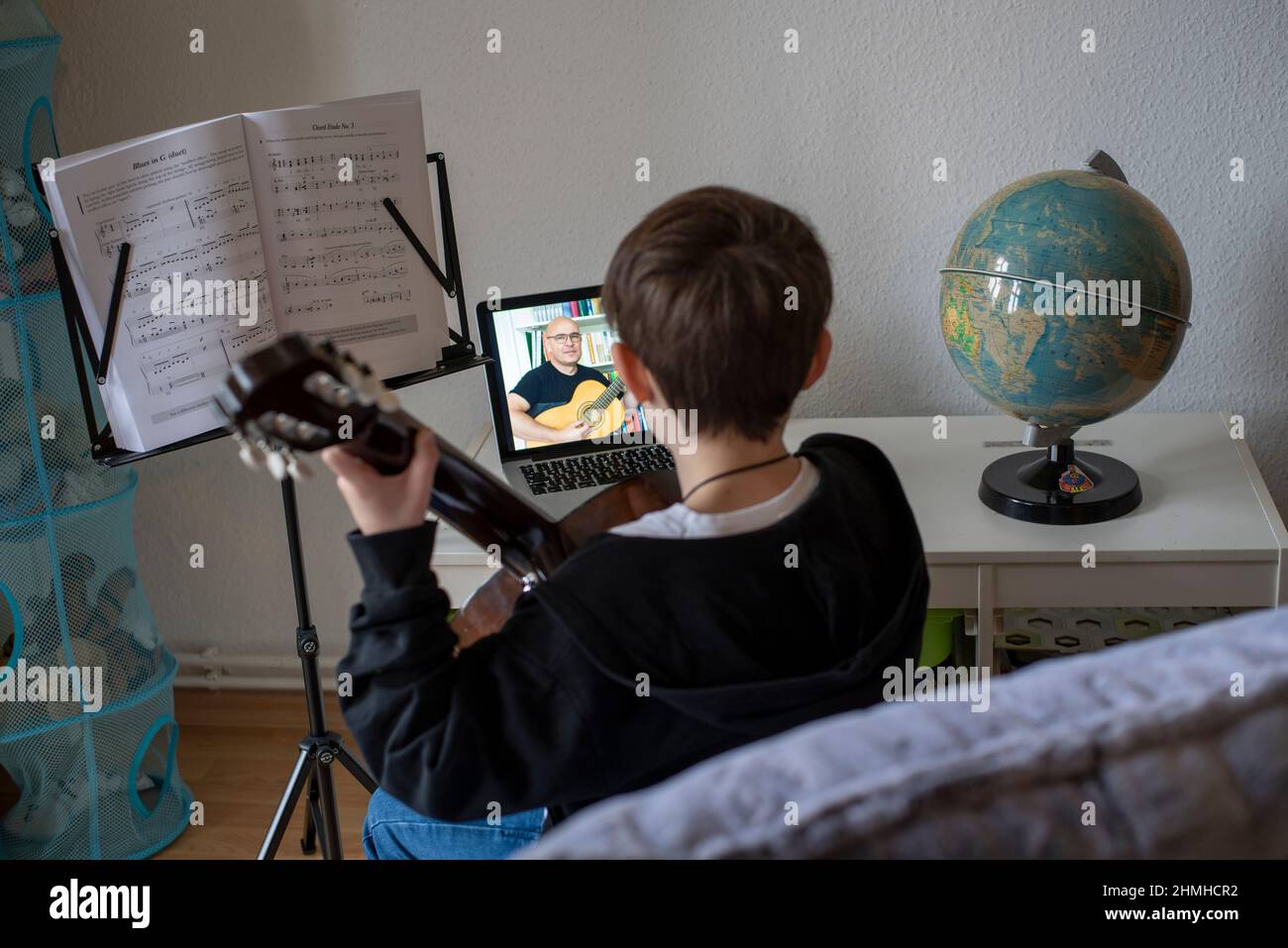 Boy learns guitar in online class. Stock Photo