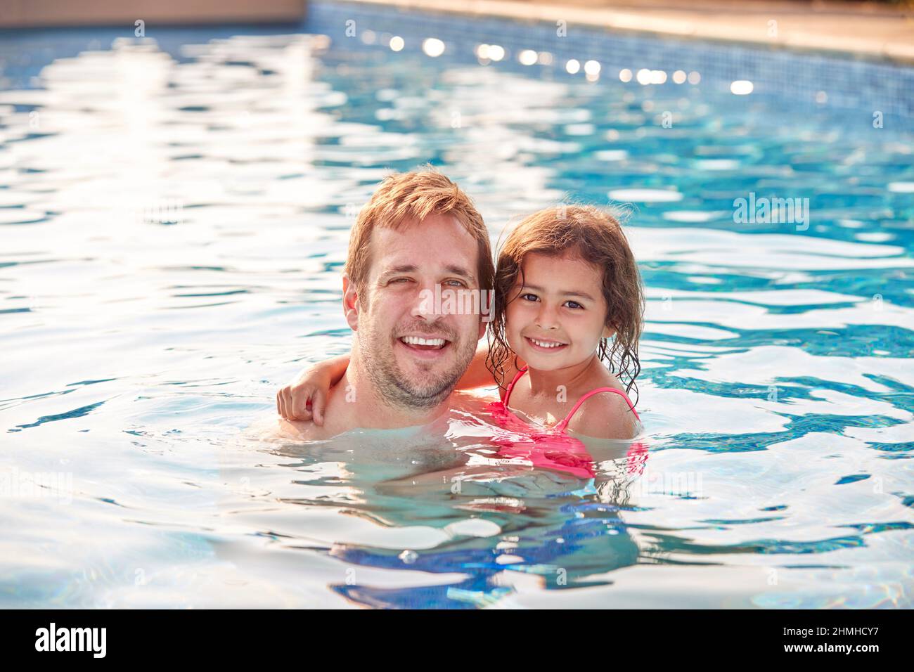 Portrait Of Father And Daughter Having Fun In Swimming Pool On Summer