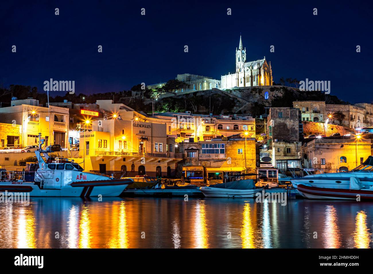 Towering over Mgarr Harbor in Gozo is the Church of Our Lady of Lourdes Stock Photo