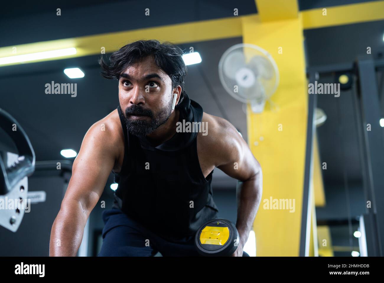 young man busy exercising using dumbells at fitness center concept of