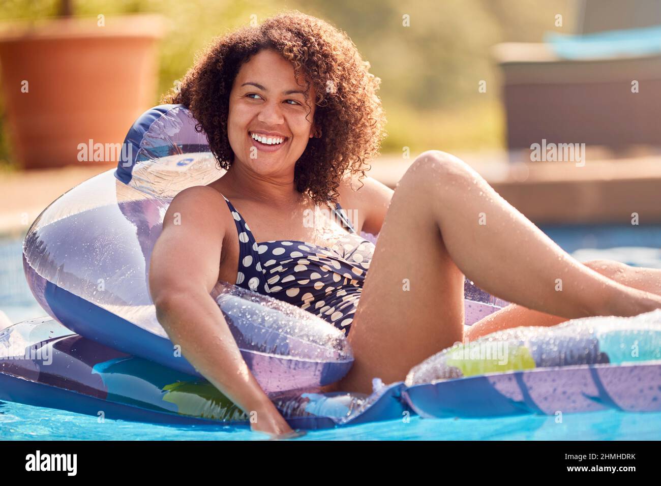 Woman Relaxing Floating On Inflatable In Swimming Pool On Summer Vacation Stock Photo