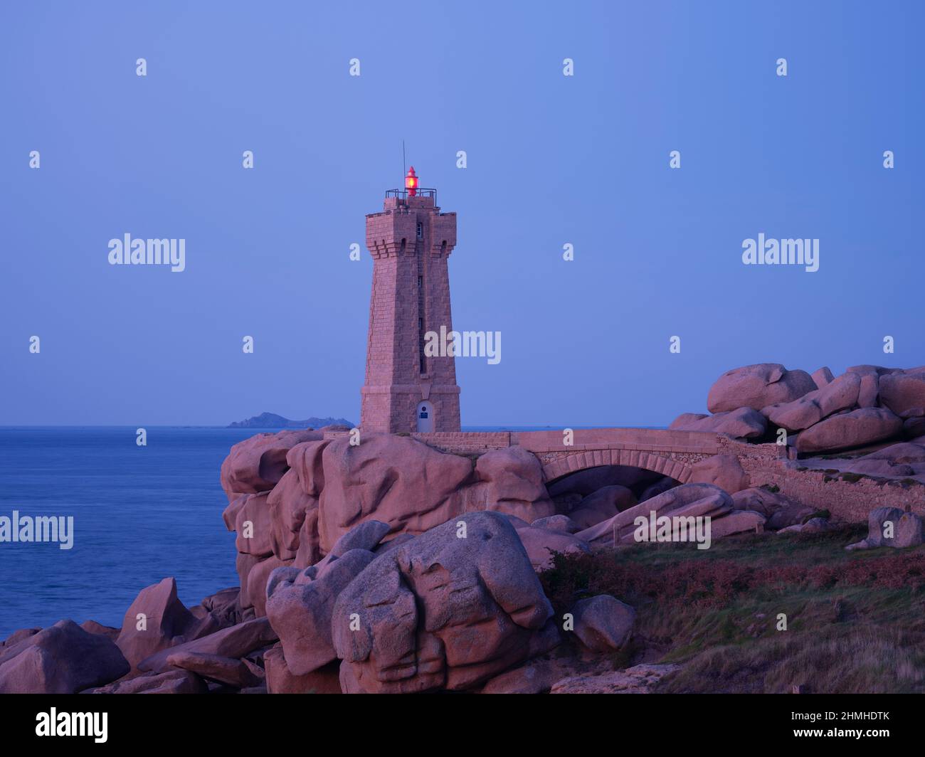 Phare de Ploumanac'h at dusk on the Côte de Granit Rose in the Côtes d'Armor department of Brittany. The lighthouse was built from the pink granite of the rocky coast and blends in harmoniously with the surroundings Stock Photo