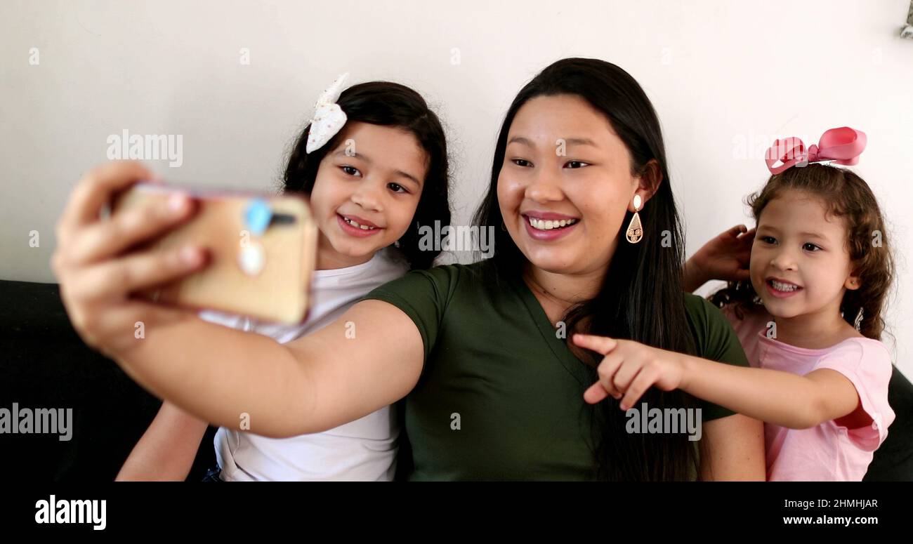 Mother and daughters talking to family member via cellphone video ...