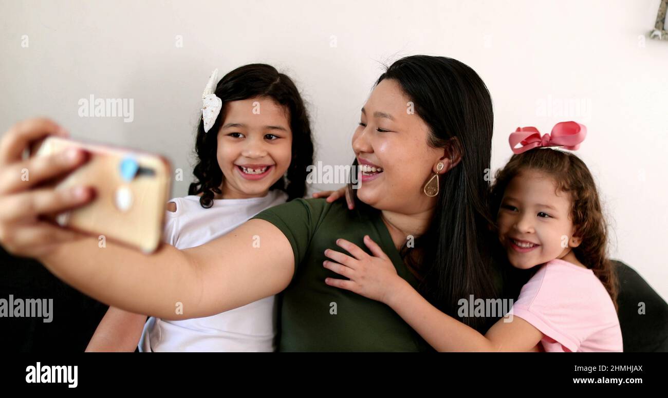 Mother and daughters talking to family member via cellphone video ...