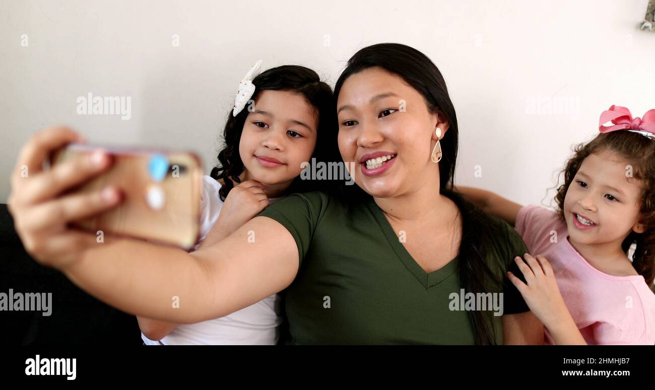 Mother and daughters talking to family member via cellphone video ...