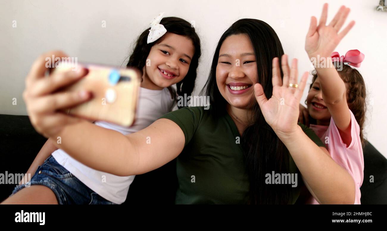 Mother and daughters talking to family member via cellphone video ...