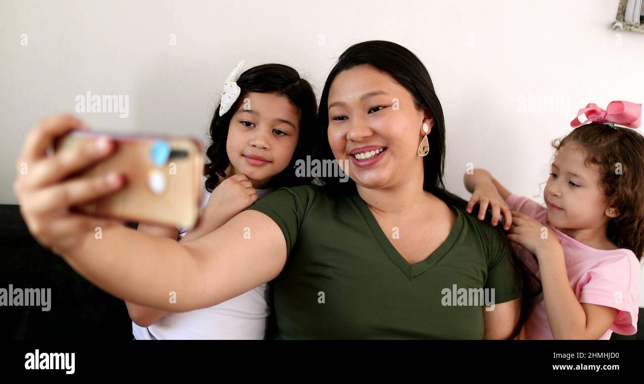 Mother and daughters talking to family member via cellphone video ...