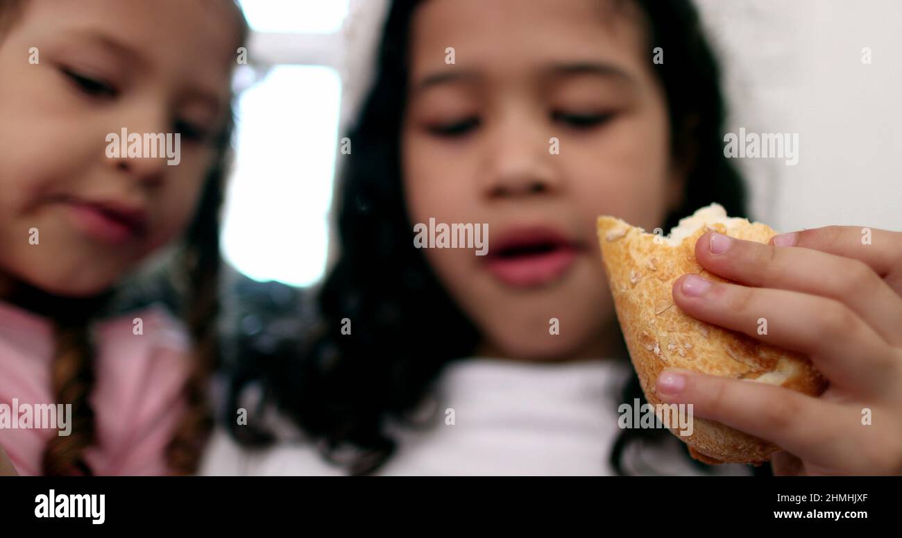 Two little girls eating sandwiches, children afternoon snack Stock