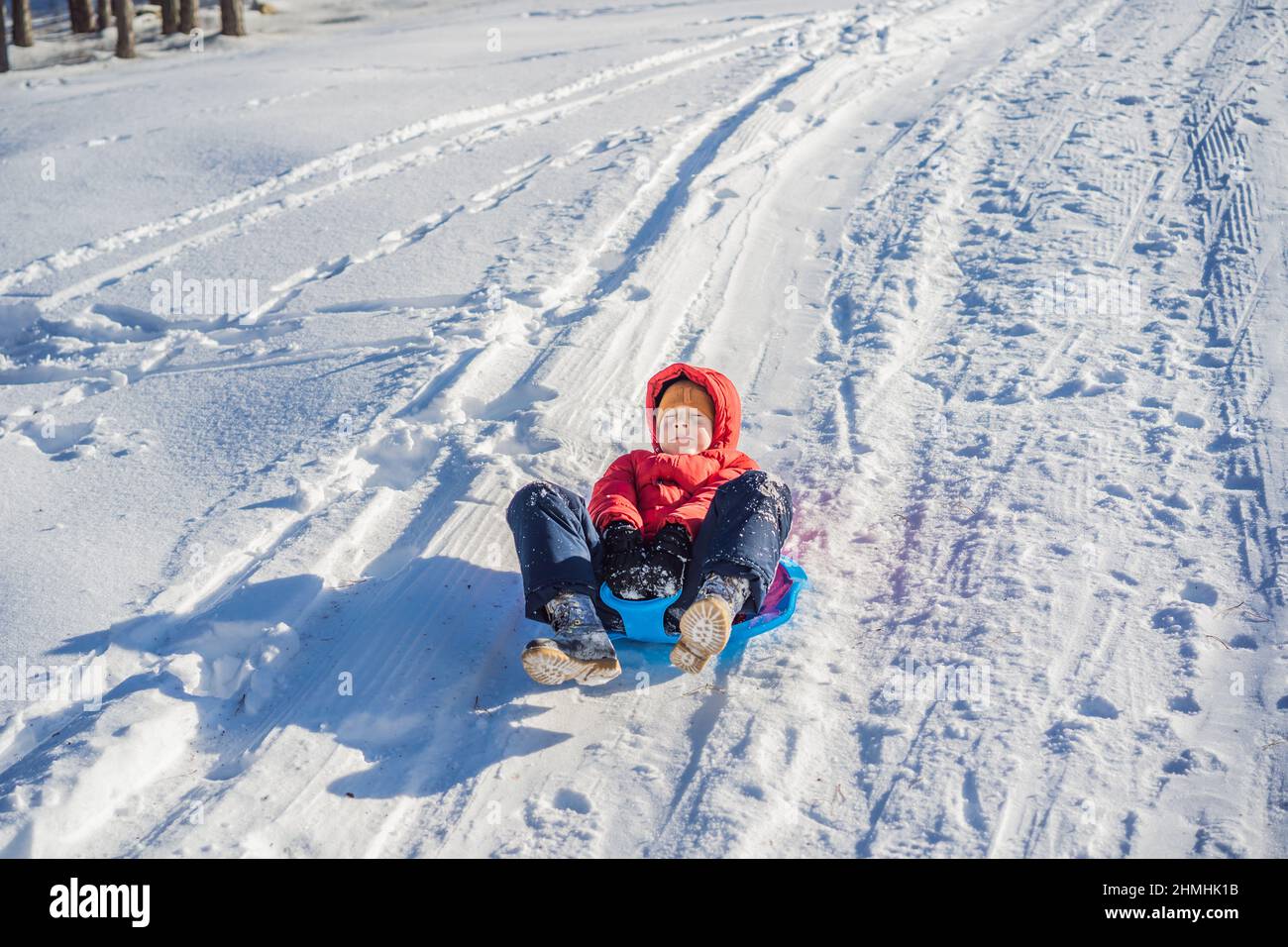 happy and positive little boy enjoying sledding and cold weather ...