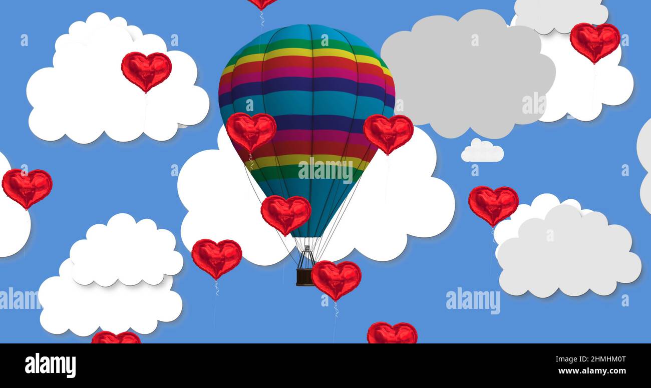 Multiple heart shaped balloons floating against hot air balloon in blue ...