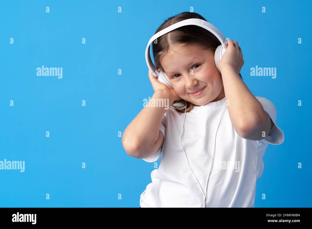 Little girl child wear headphones listen to music over blue background