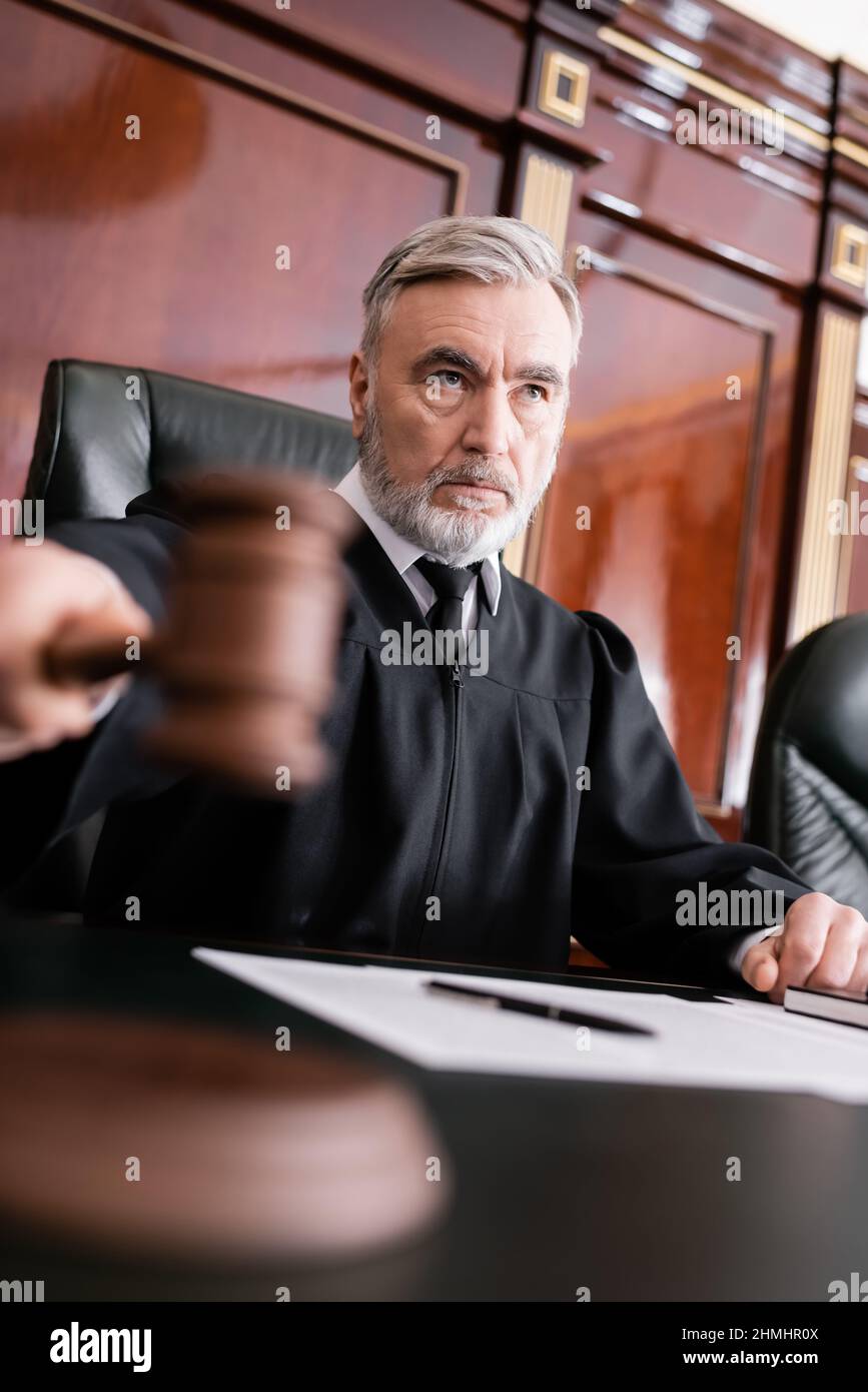grey-haired judge with blurred gavel sentencing in courthouse Stock Photo