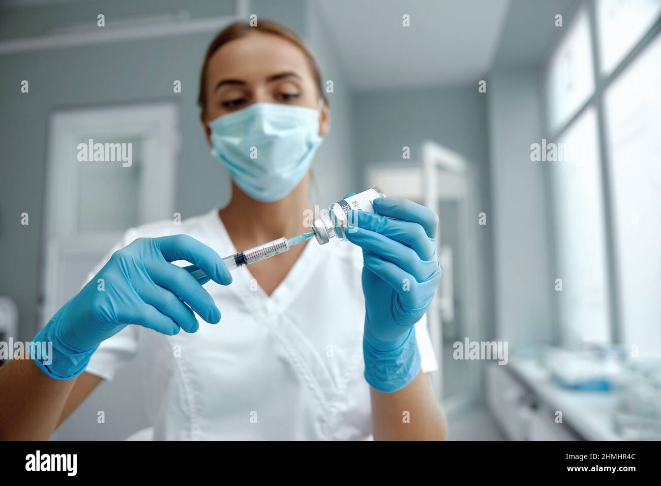 Woman doctor in laboratory holding a syringe with vaccines. Female holding COVID-19 vaccine in hand.  Concept:diseases,medical care,science. Stock Photo