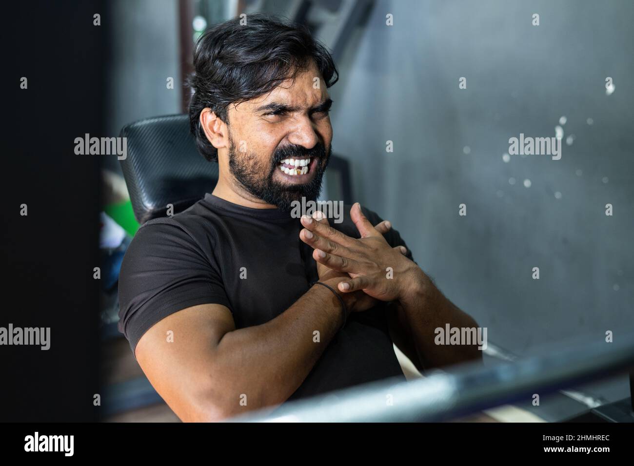 young man suffering from chest pain during weight lifting at gym