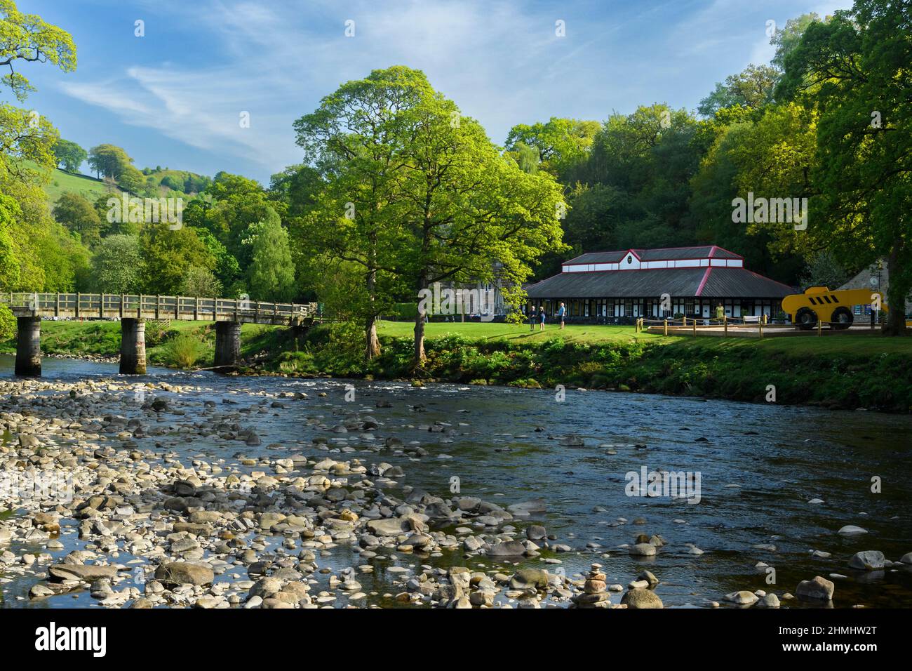 Beautiful scenic summertime countryside (Cavendish Pavilion cafe & visitors on riverbank) - sunny Bolton Abbey Estate, Yorkshire Dales, England, UK. Stock Photo