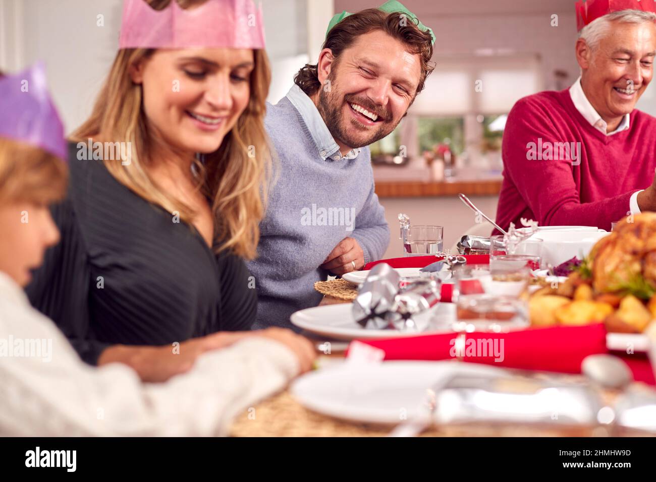 Multi Generation Family In Santa Hats Enjoying Eating Christmas Meal At ...