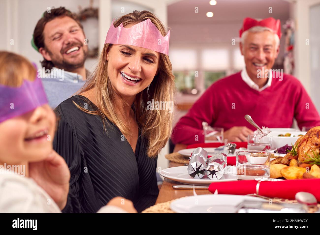 Multi Generation Family In Santa Hats Enjoying Eating Christmas Meal At ...