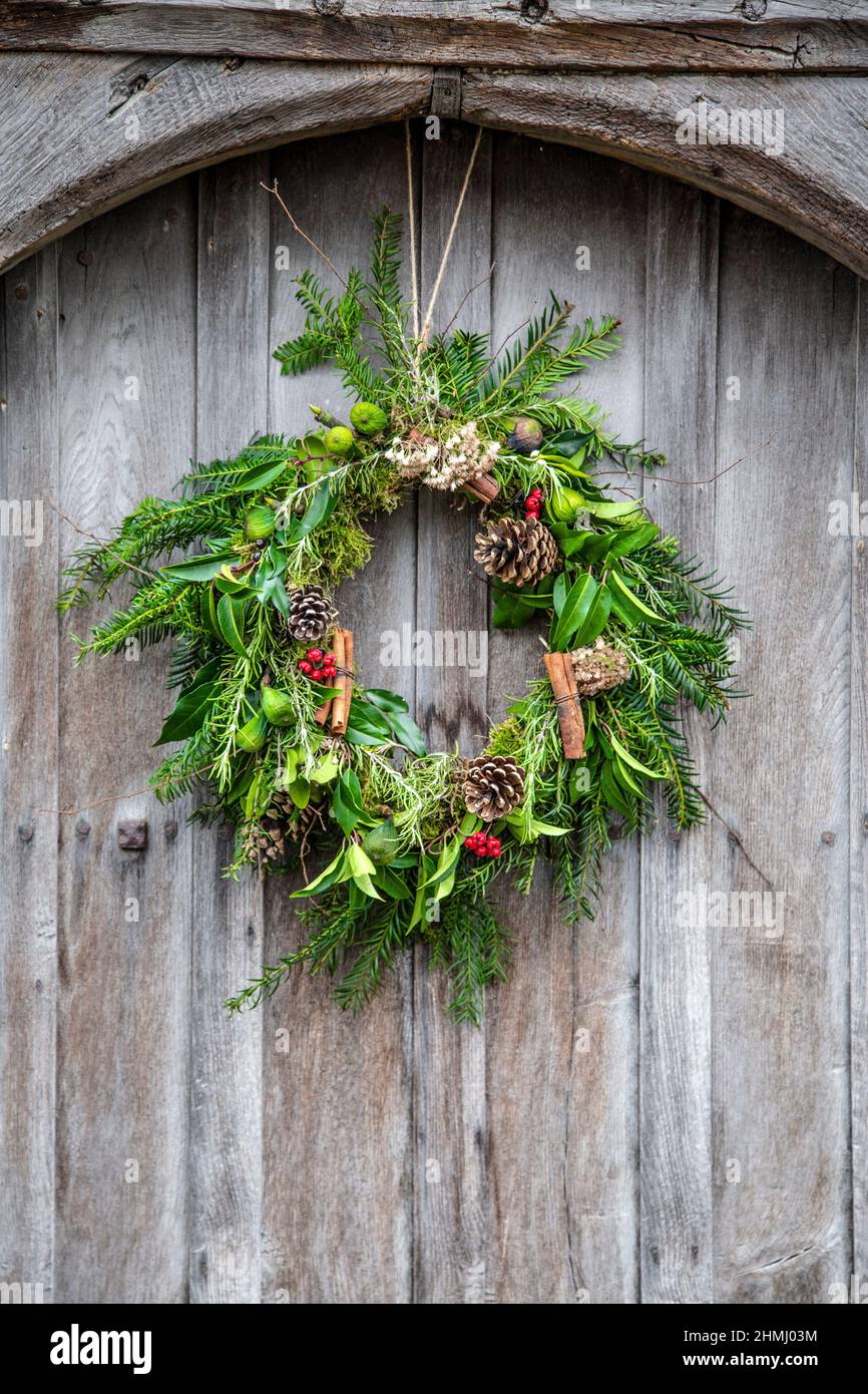 Christmas wreath with pine cones, leaves and twigs on a wooden door (Ashwell, Hertfordshire, UK) Stock Photo