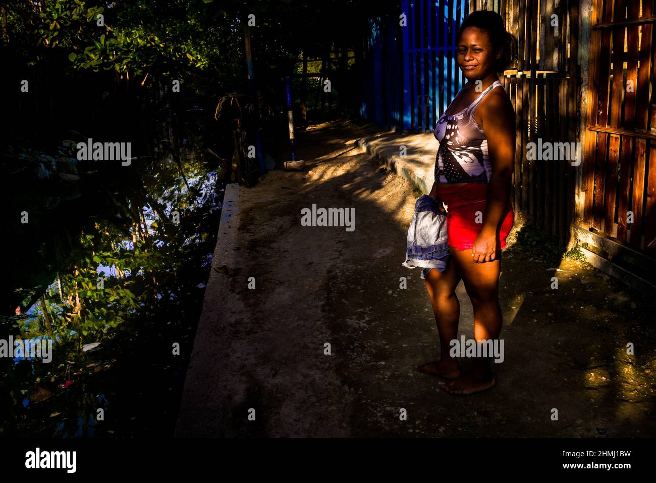 An Afro-Colombian woman poses for a picture next to an open sewer in Olaya Herrera, a low social class neighborhood in Cartagena, Colombia. Stock Photo
